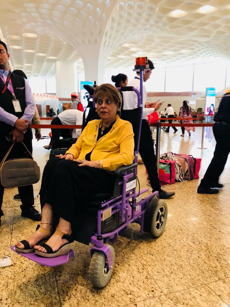 Senior passenger seated in a motorized airport wheelchair near the arrivals hall at Delhi airport